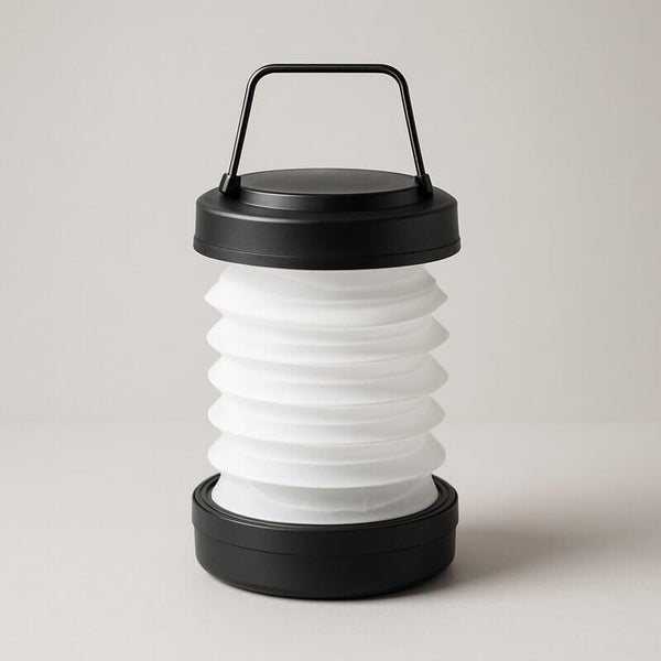 Fold-flat LED travel lantern with a sleek black handle and collapsible silicone shade for luxury adventure lighting.