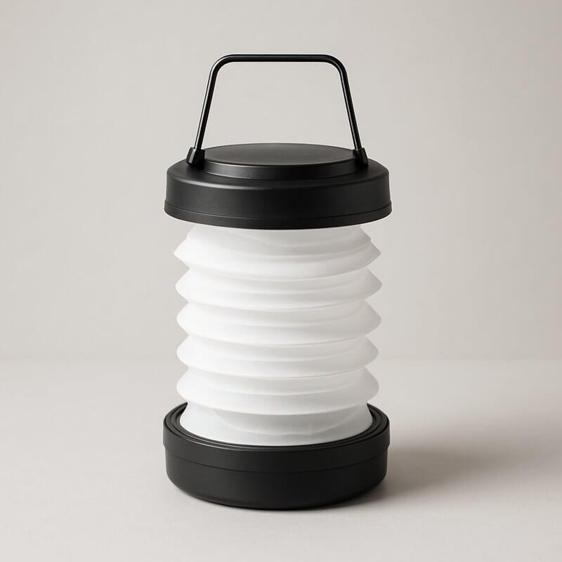 Fold-flat LED travel lantern with a sleek black handle and collapsible silicone shade for luxury adventure lighting.